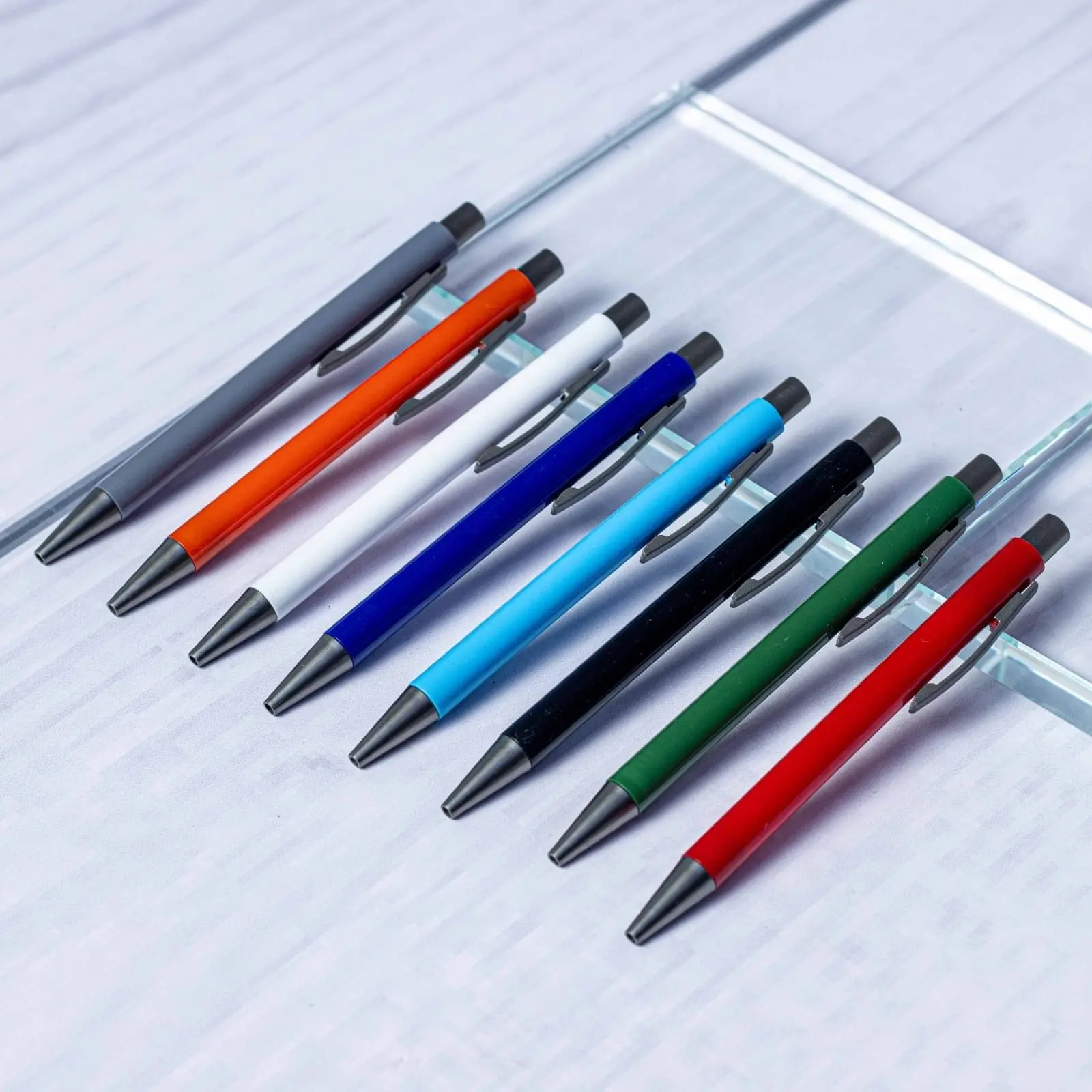 Row of plastic pens with coloured barrels on a glass display, Hensa