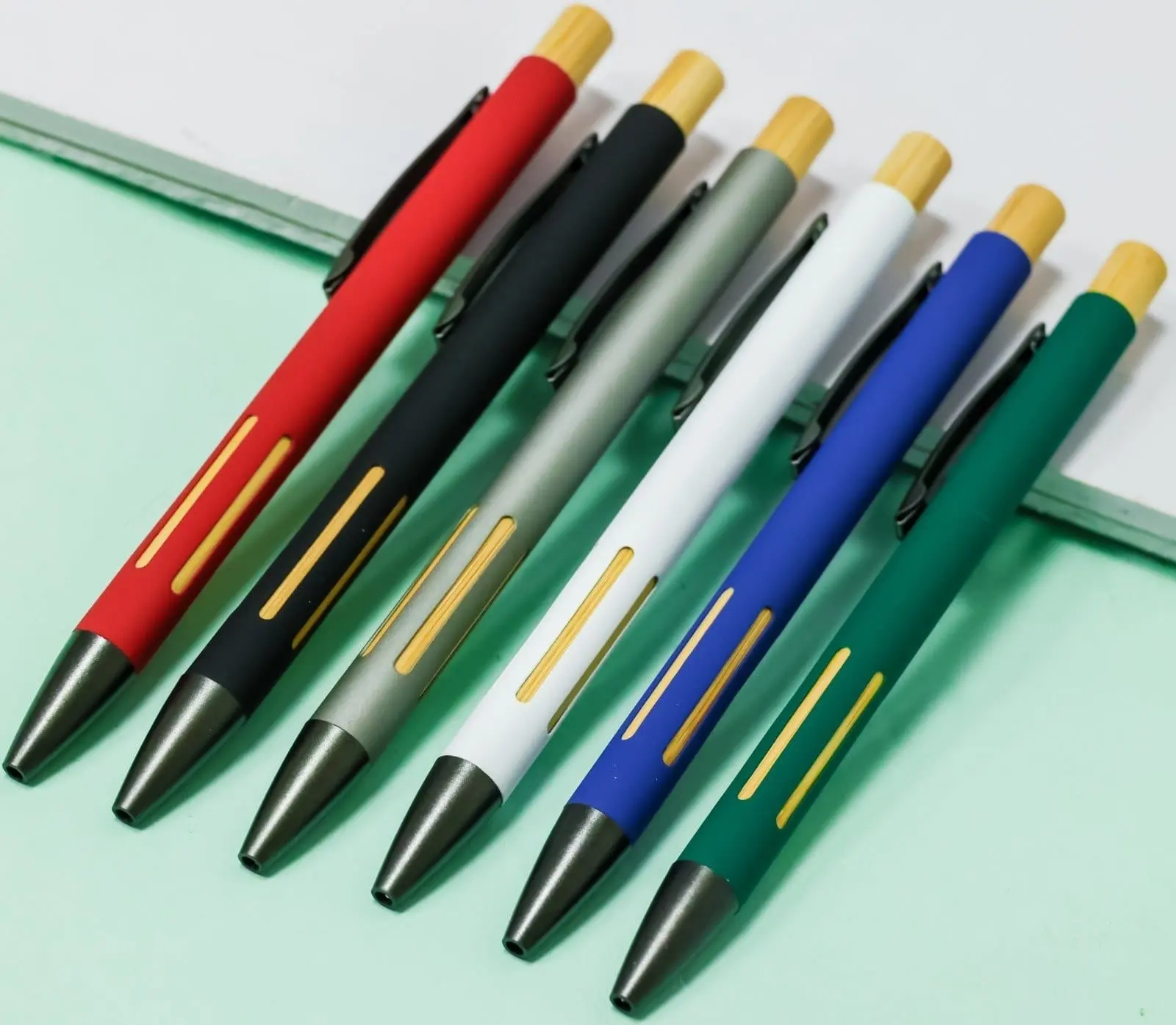 Six click pens in red, black, grey, white, blue and green with wooden tops and gold slot details, Hensa