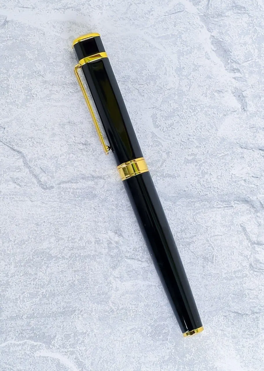Glossy black metal pen with a gold clip, gold ring and gold end lying on a grey stone surface, Hensa