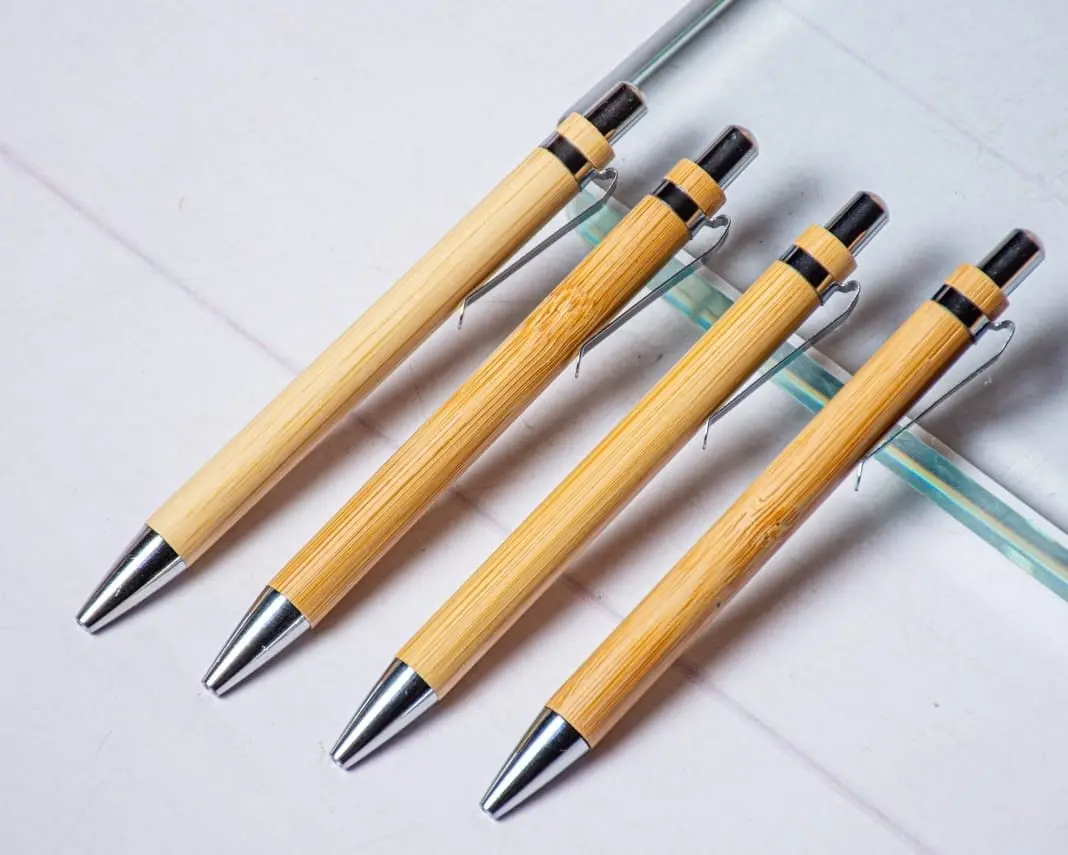 Four bamboo click pens with chrome tips and black rings on a white surface, Hensa