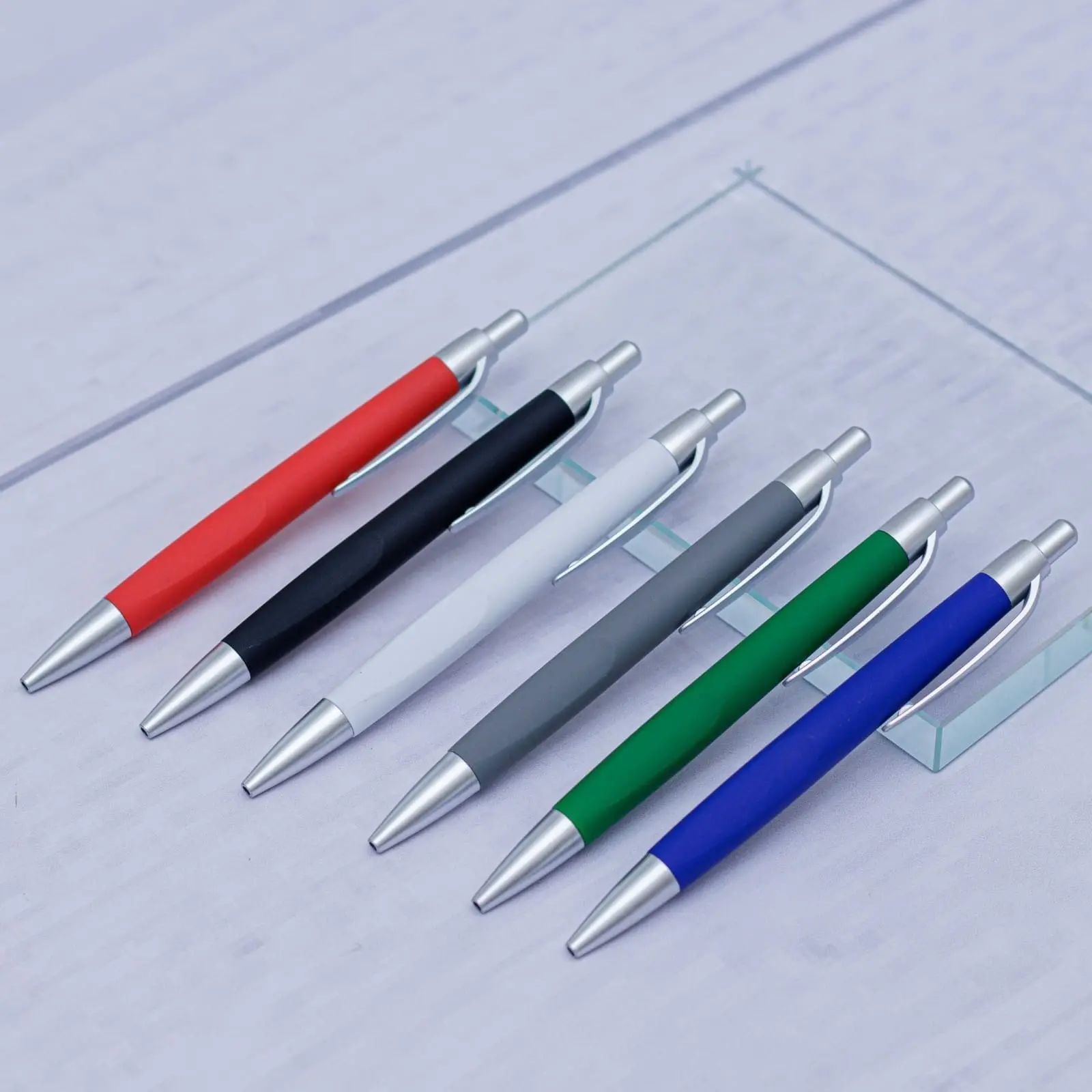 Row of matte plastic pens in several colours on a glass display, Hensa