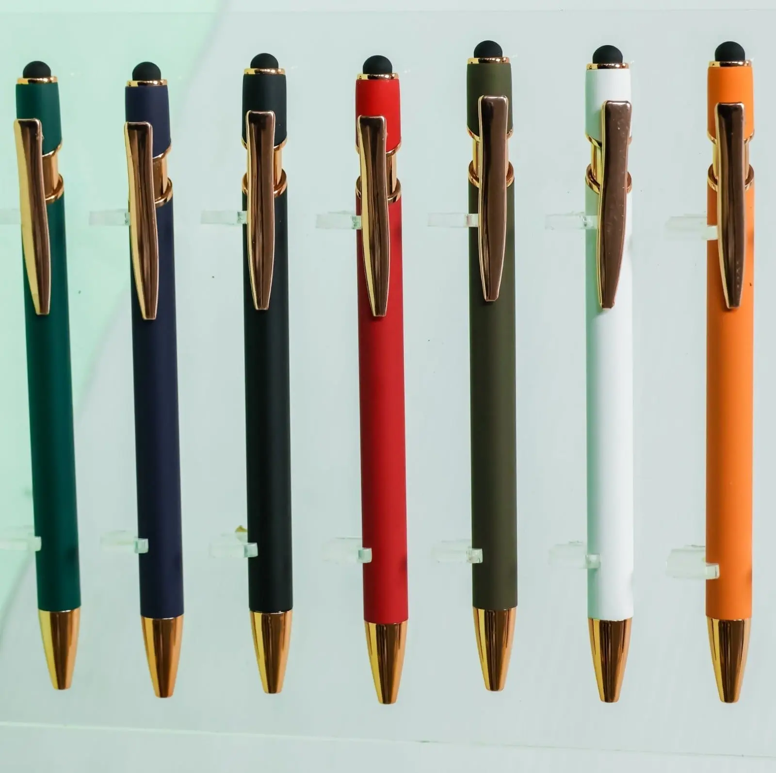 Seven click pens in green, navy, black, red, olive, white and orange with rose gold clips and tips, Hensa