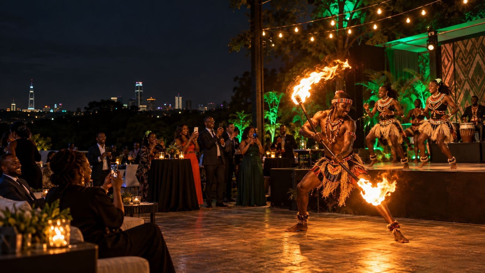 A fire performer spinning a flaming staff at a night event while dancers perform on the stage behind