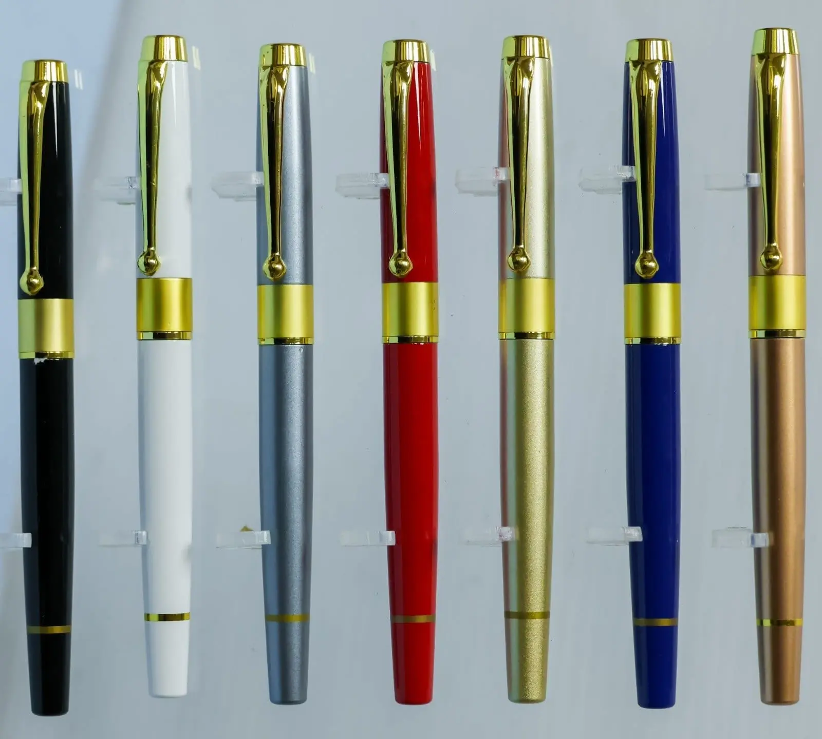 Seven metal pens in black, white, grey, red, gold, blue and copper with gold clips and bands, Hensa
