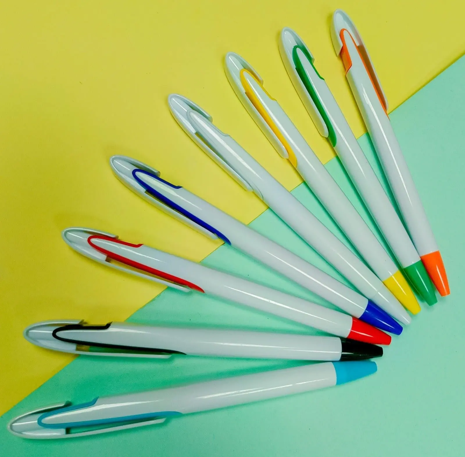 Eight white plastic pens with coloured clips and tips fanned out, Hensa