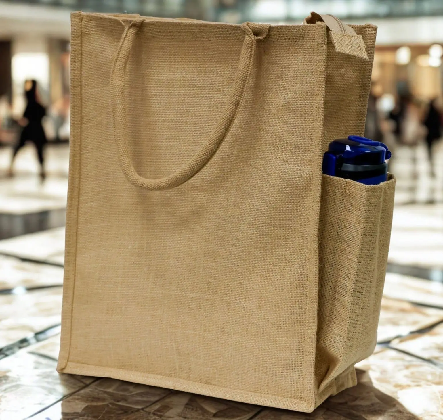 Tall natural jute bag with a side pocket holding a blue bottle, Hensa