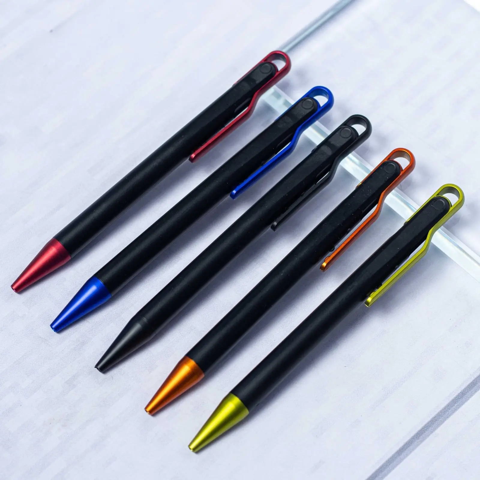 Five matte black pens with coloured loop clips in red, blue, orange and yellow, Hensa