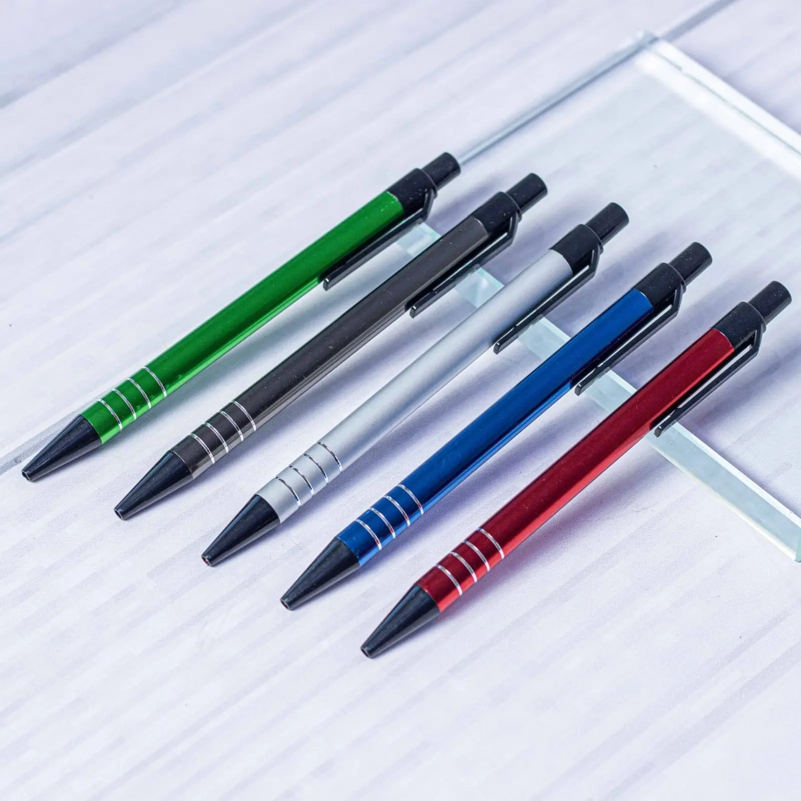 Five metal click pens with engraved rings in green, grey, silver, blue and red, Hensa