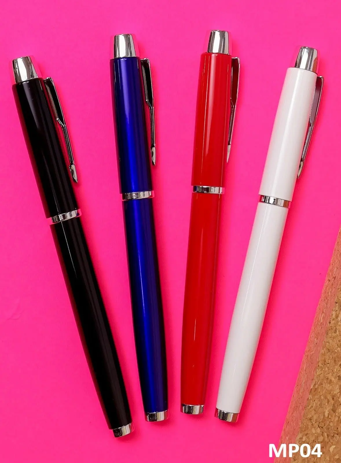 Four metal pens in black, blue, red and white with chrome clips and rings on a pink surface, Hensa